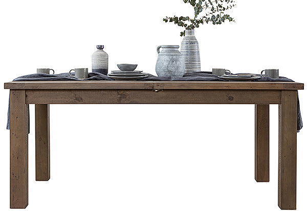 Reclaimed wood dining table with a dark, cold finish and pottery, tableware and plants on top of the table