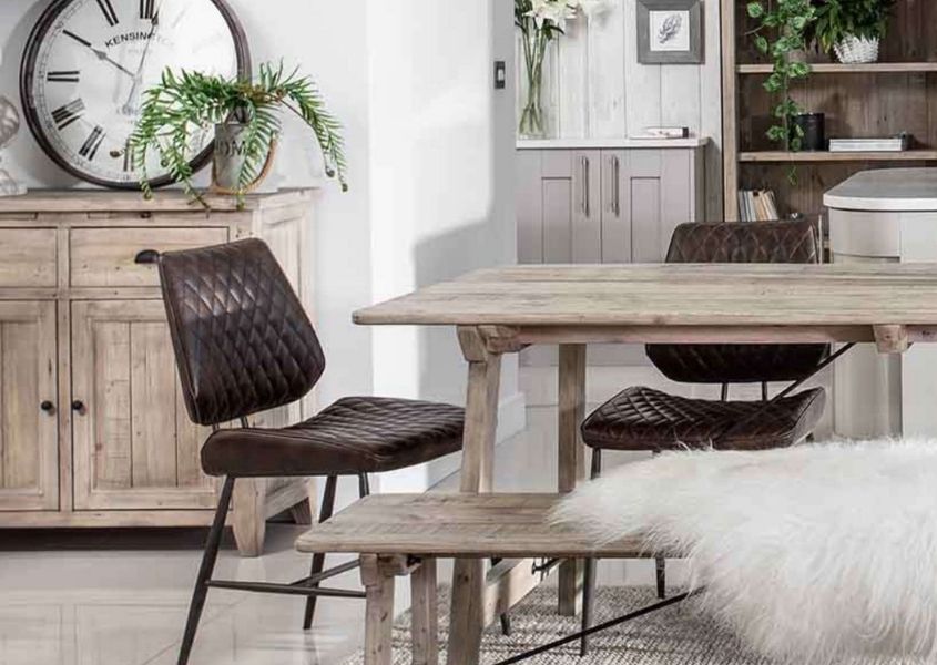 Dining room with pale reclaimed wood dining table and wooden bench with brown faux leather dining chair and rustic sideboard