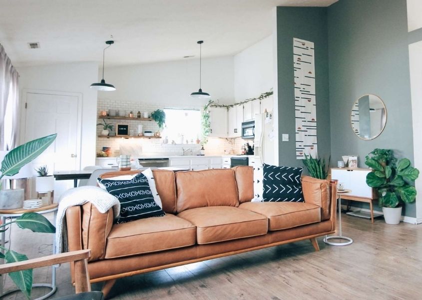 Brown leather sofa in open plan living room and white kitchen in background