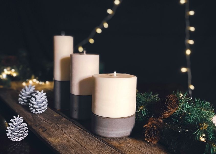 white candles with black concrete base on rustic wooden tabletop