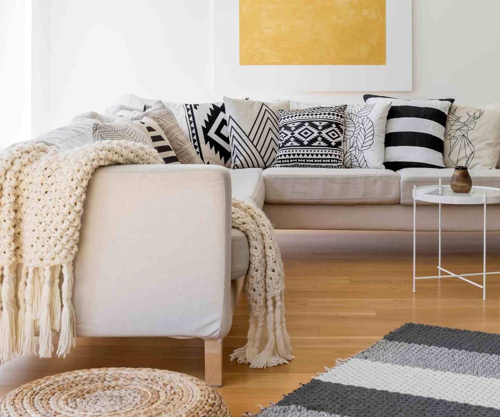 Cream modern sofa with white chunky knit throw and black and white cushions