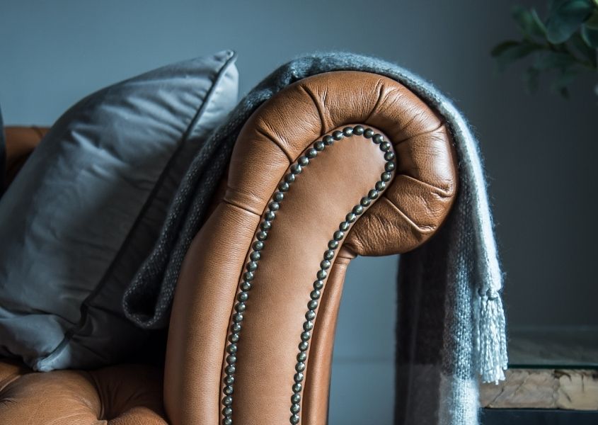 brown leather sofa with blue cushion and blanket