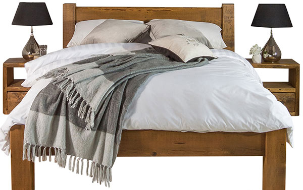 Reclaimed wood bed frame with two bedside tables and lamps, white duvet and a throw