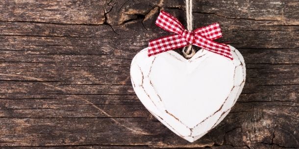Wooden heart with red gingham ribbon on rustic wood