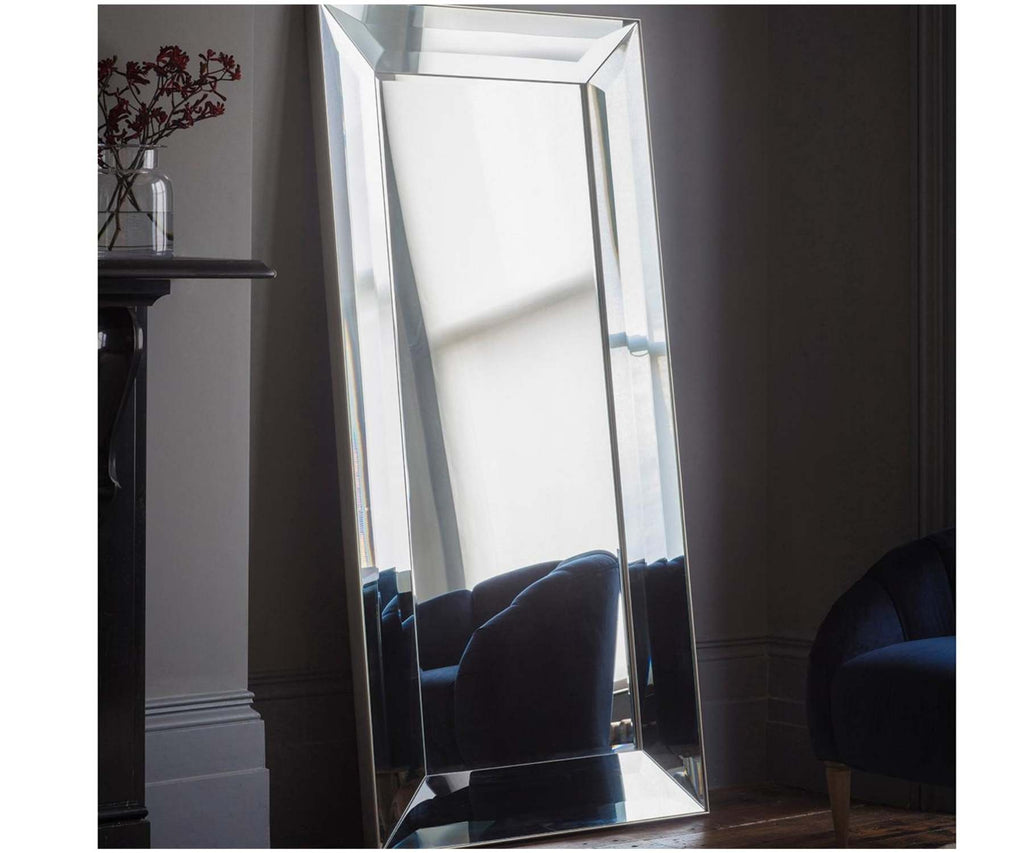 Large floor mirror in dark room and armchair