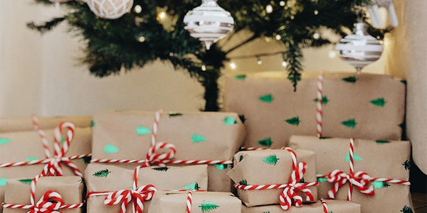 Many small Christmas gifts with red ribbons underneath a decorated Christmas tree