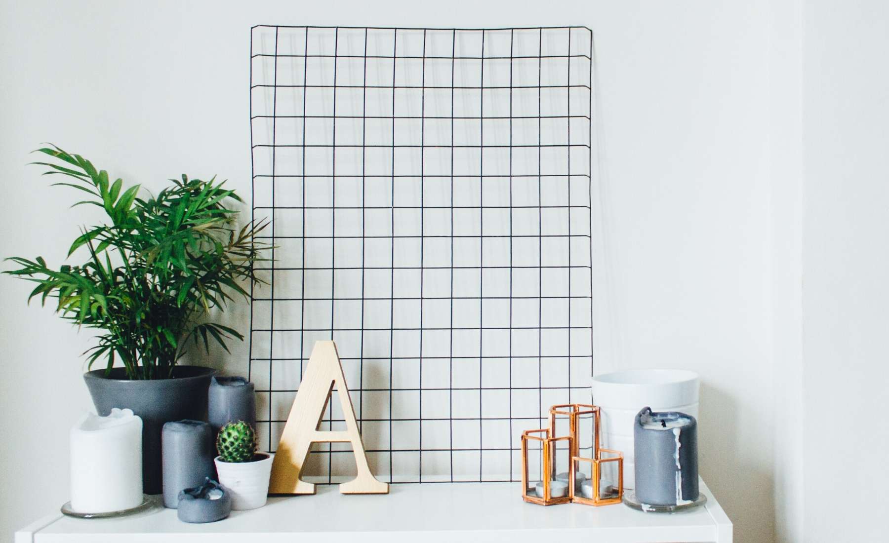 Desk with plant, letter and wire frame on wall