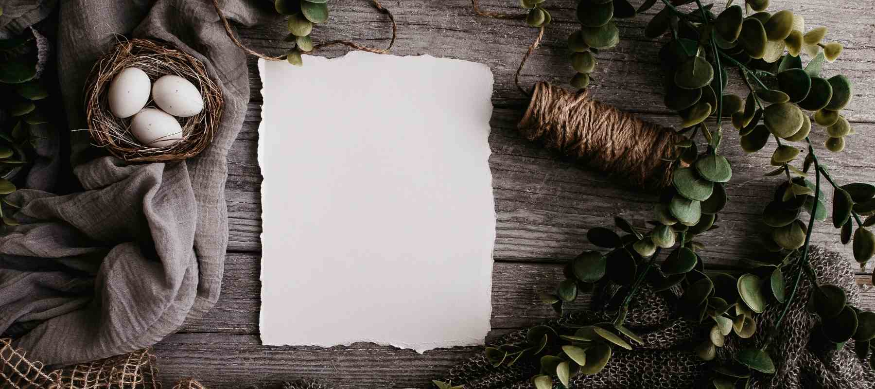 White paper, eggs and green leaves to make a wreath