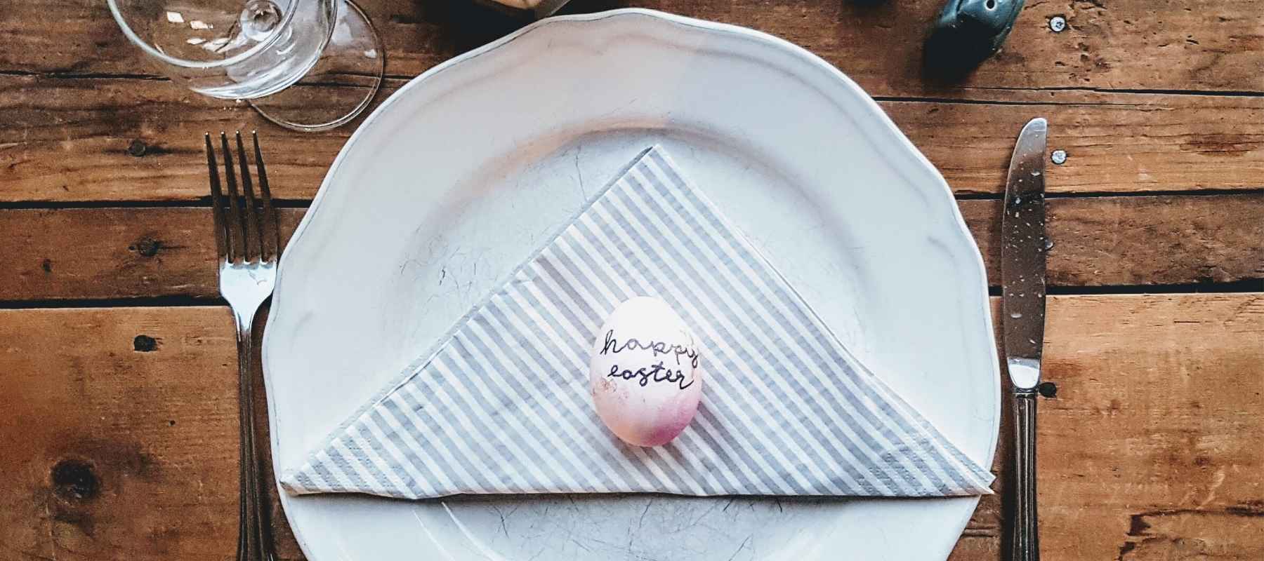 White dinner plate on wooden table with happy easter egg