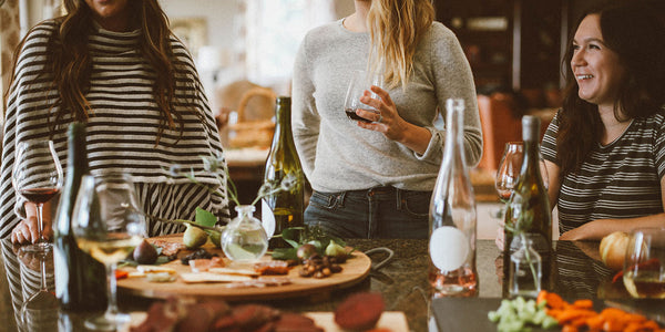 Friends standing around a dining table with food and drinks