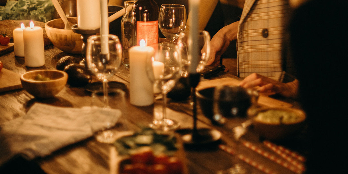 People huddled around a rustic dining table with lit candles