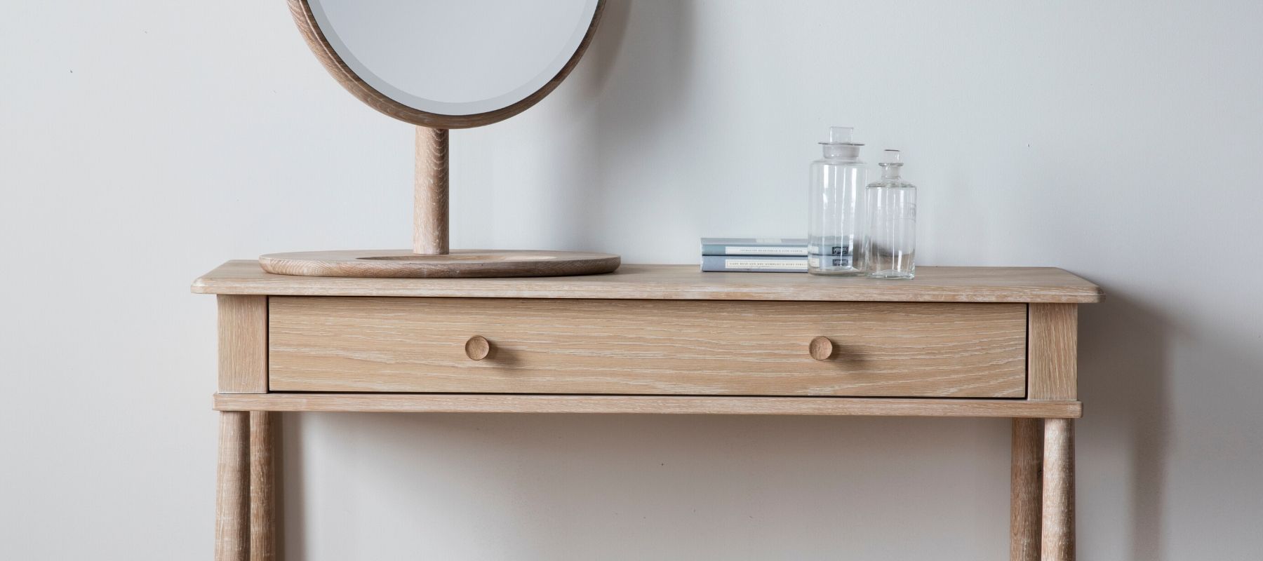 Close up of pale wood dressing table with round wooden mirror