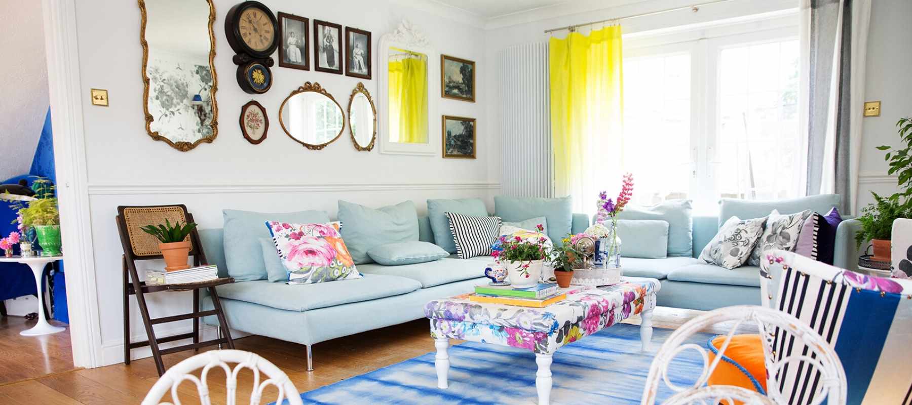 Wall display of mirrors and clocks with pale blue sofa