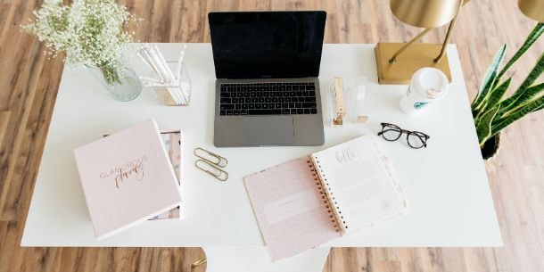 White desk with laptop and flowers in glass jar