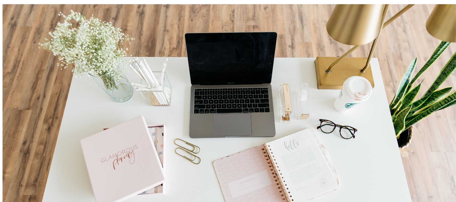 Laptop and note pads on a white desk