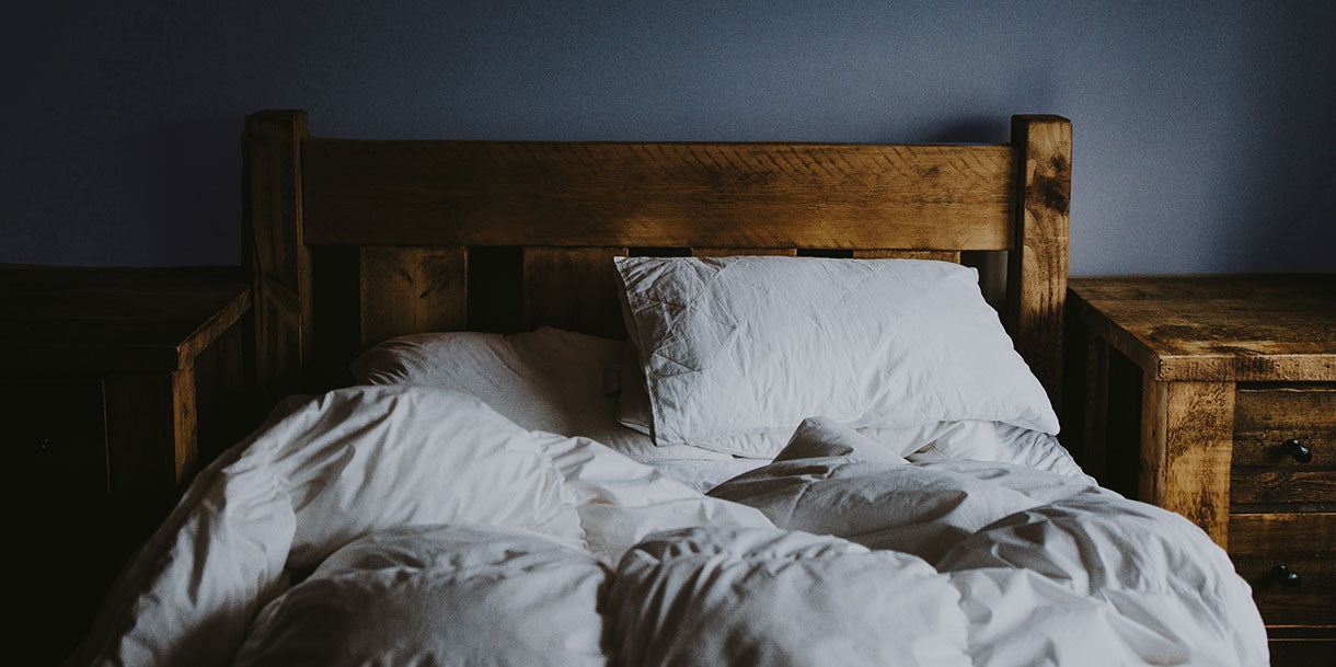 A rustic wooden bed with white bedding in a bedroom