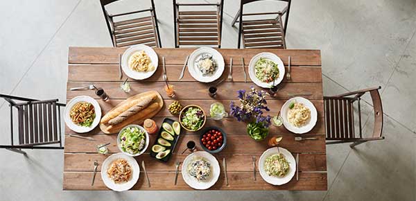 A wooden dining table with plates and food on top and wooden dining chairs around