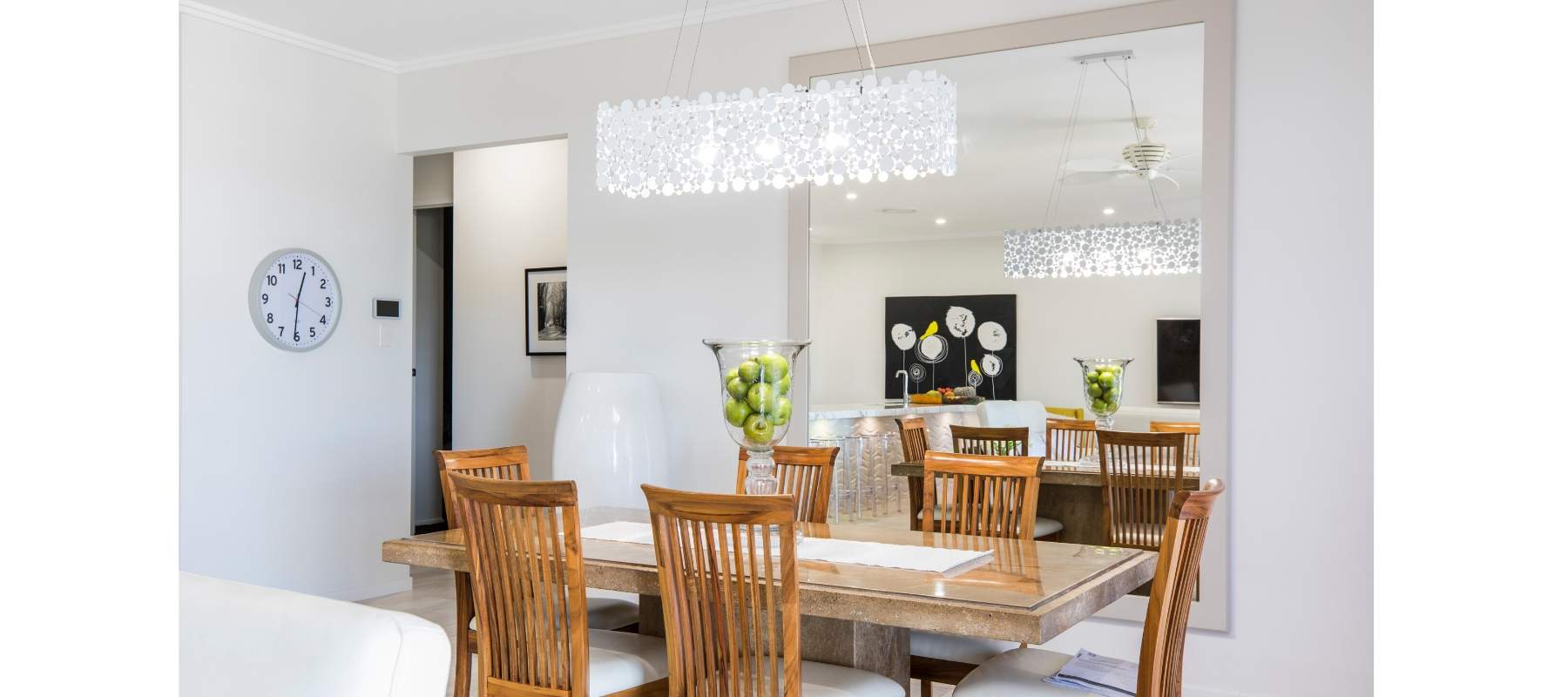 Oversized mirror on the wall with dining room table and chairs