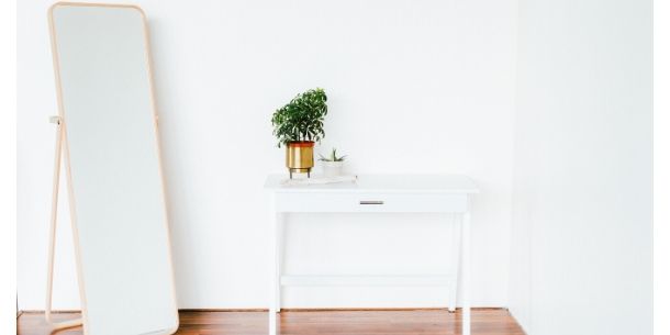 Freestanding wooden floor mirror with white console table and green plant