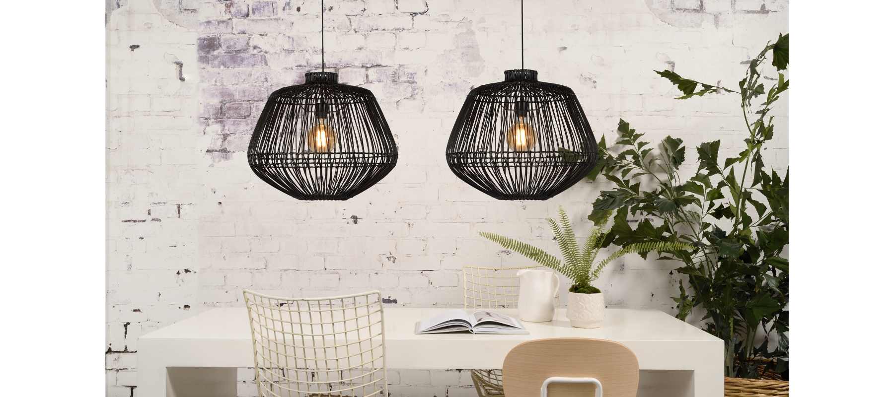 Black rattan pendant lights against white brick wall