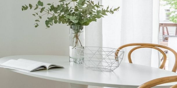 white oval dining table with wood chairs and eucalyptus leaves in glass jar