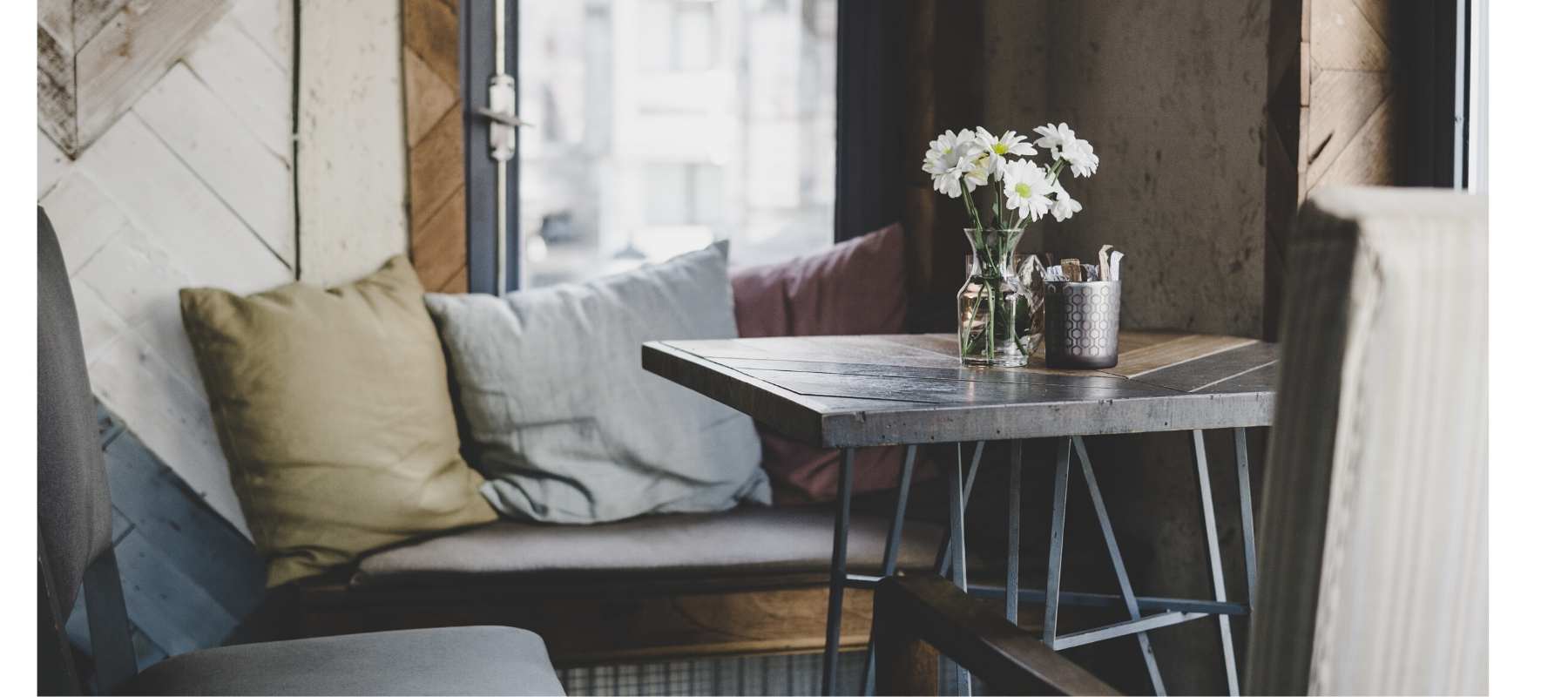 Small wooden table with glass jar and white daisies