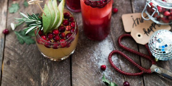 A reclaimed wood table with a pair of red scissors, red berries and Christmas tags