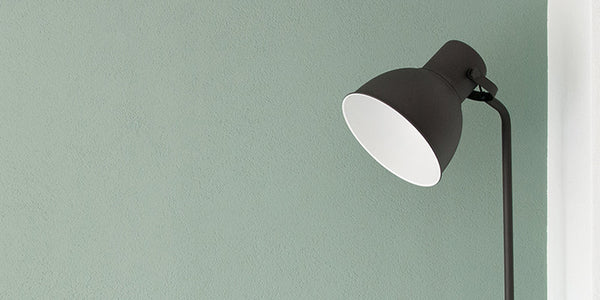 Mint green wall paint with a black metal floor lamp in front of it