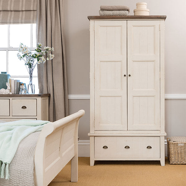 A painted wooden wardrobe with two doors and drawers at the bottom