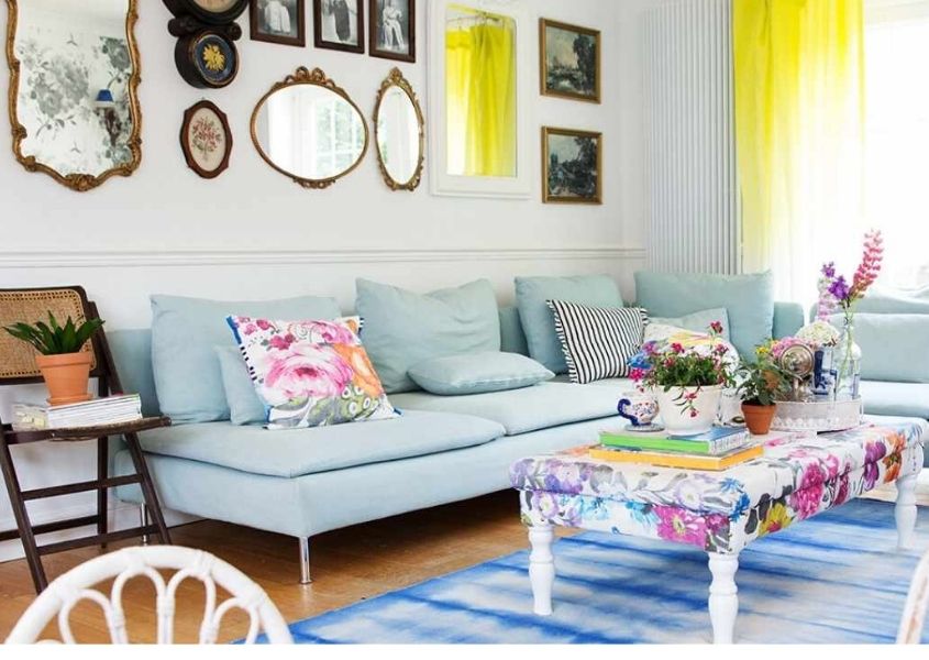 Pale blue sofa with white coffee table and display of mirrors on the wall