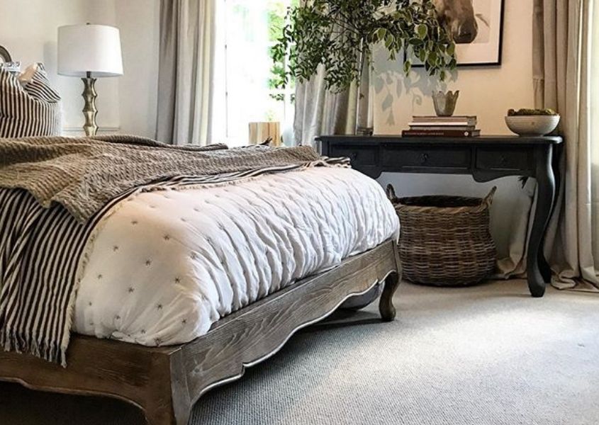 View of a bedroom with wooden bed frame and dark wood dressing table