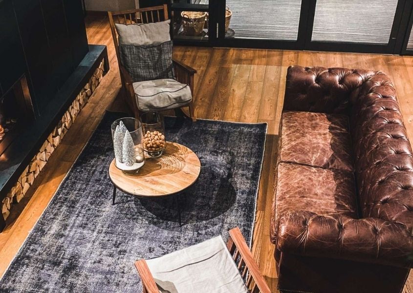 rustic living room with brown leather sofa and wooden armchairs