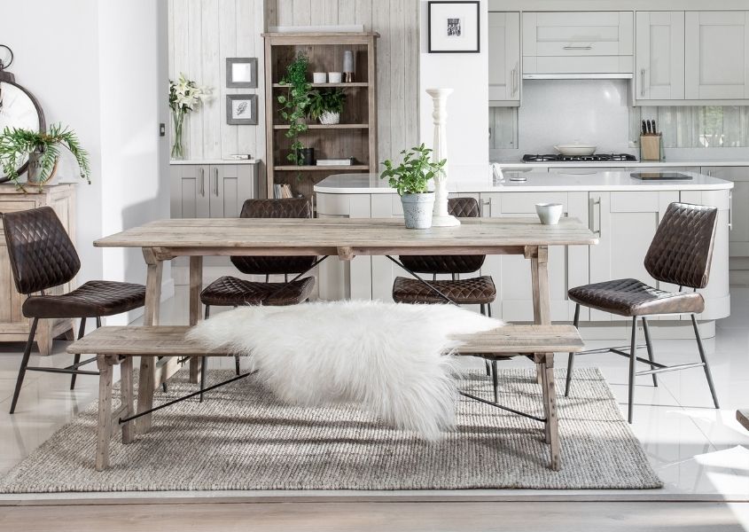 Reclaimed wood dining table in pale wood with matching bench and brown dining chairs