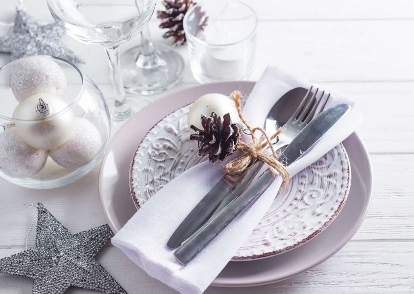 White and silver Christmas dining table decorations on white rustic dining table