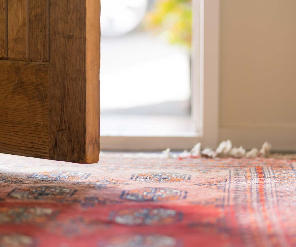 Close up of rustic front door with red rug on floor