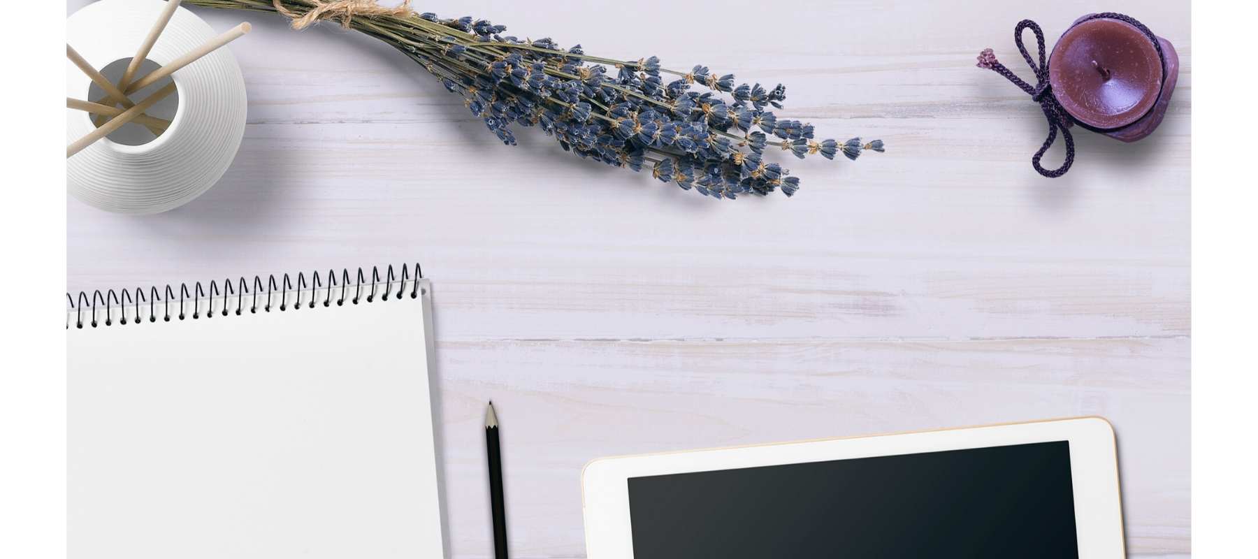 Scented candle, diffuser, lavender and notebook on white desk