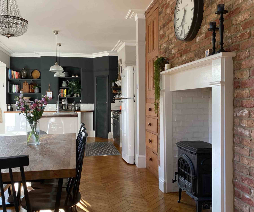View of kitchen from dining room with exposed brick wall and dark grey feature wall