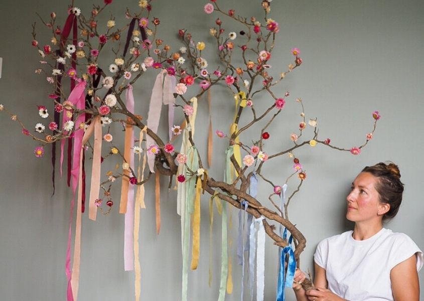 Woman in white t-shirt holding brand decorated with dried flowers and colourful ribbons