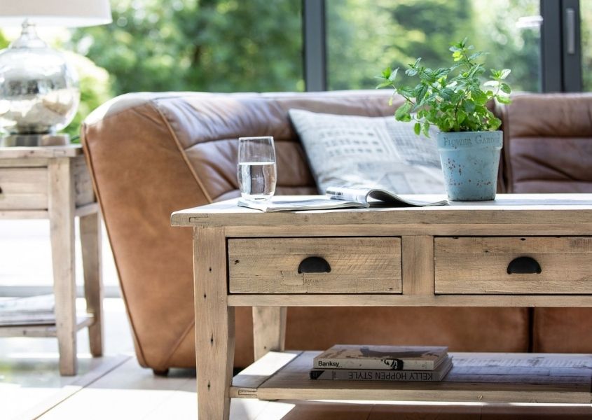 Reclaimed wood coffee table with two drawer and brown leather sofa behind