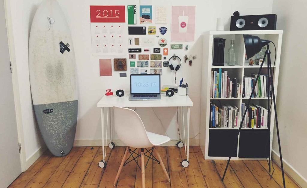 White desk with white chair and surf board in corner of room