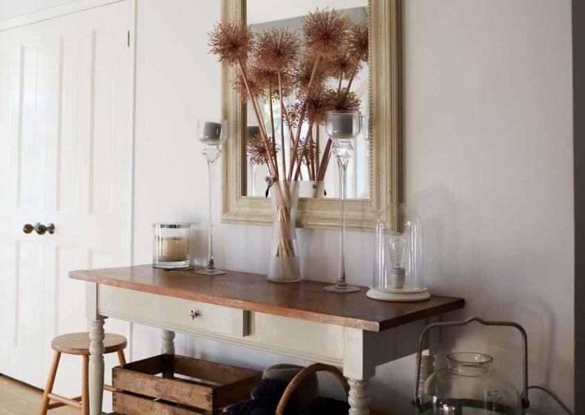 Wooden console table with large dried flower arrangement and mirror on wall