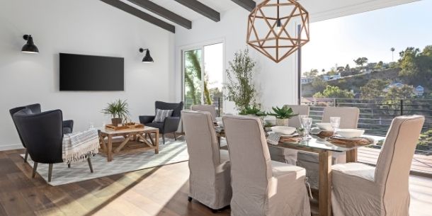 Open plan dining space and living room in front of large window with large hanging pendant light