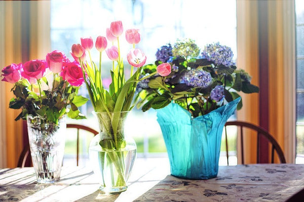 Fresh flowers in dining room on reclaimed wood dining table with wooden dining chairs