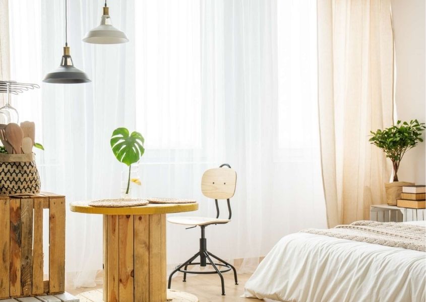 Bedroom with recycled palette round table and light pink curtains
