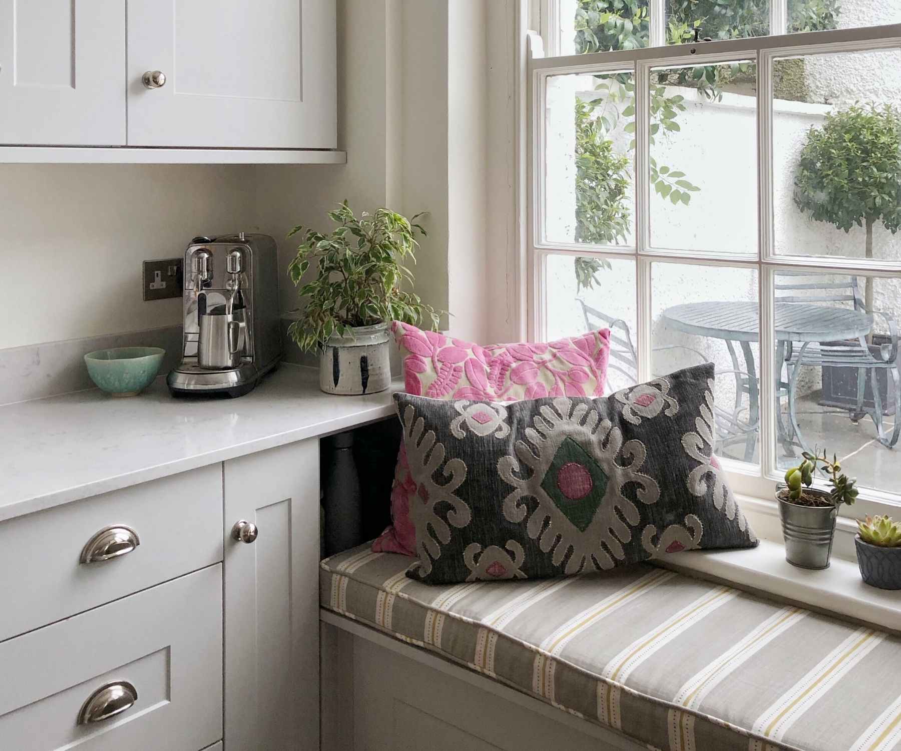 Window seat with striped padded seat and grey cushion