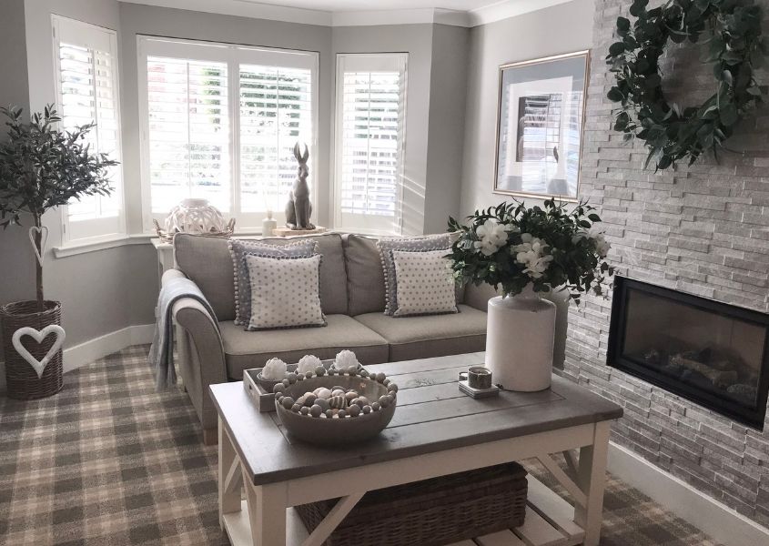 Living room with rustic coffee table and grey brick chimney breast with large bay window
