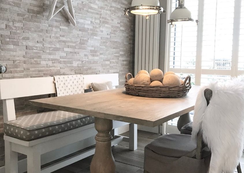 Refectory style wooden dining table with grey brick wall and white wooden bench