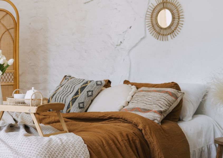 boho style bed with brown bed throw and large cushions