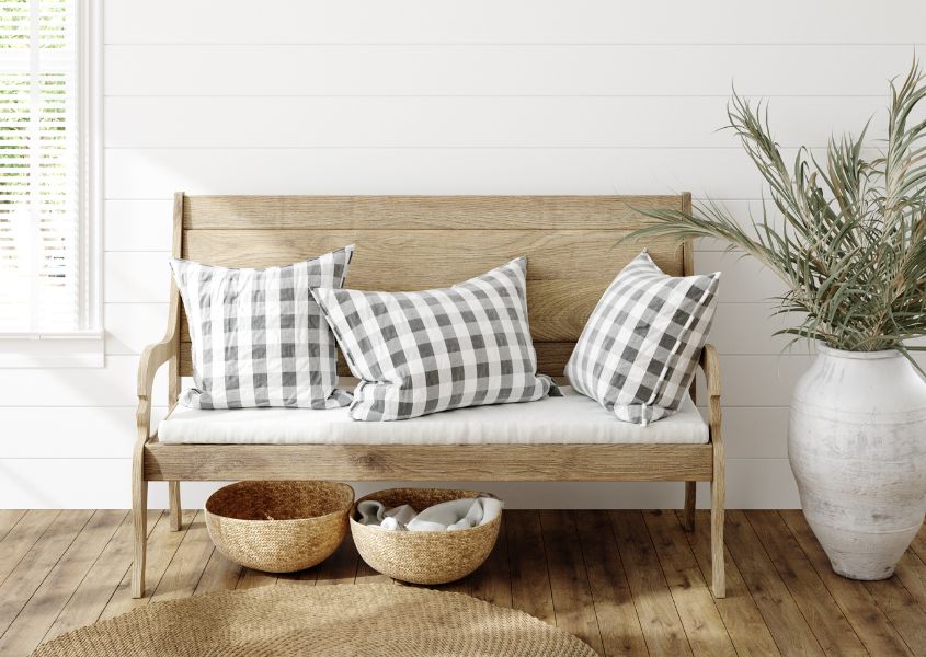 wooden bench with checked cushions and round rug