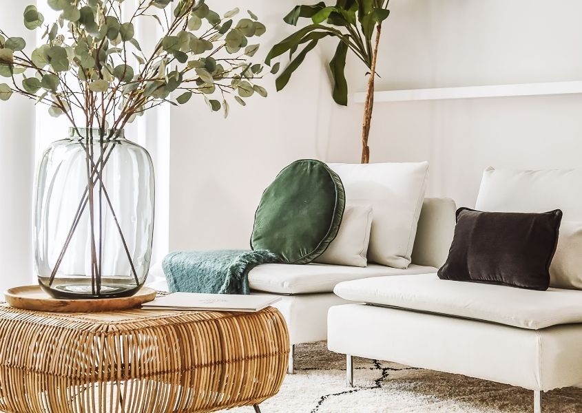 white sofa with bamboo coffee table with large glass vase and dried leaves